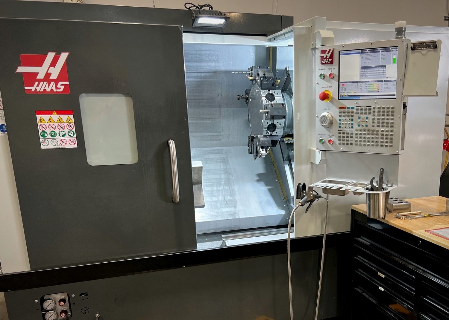 Multi-axis turning center with door open showing the chuck and turret, control pendant at right